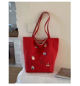 Détail d'un sac cabas en toile rouge avec broderie et anses doubles rayées
