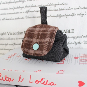 Detailed close-up of a mini denim coin purse with a brown plaid flap and blue button