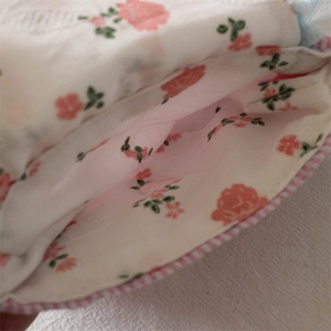 Detailed view of floral storage case with pink mesh lining and checkered piping