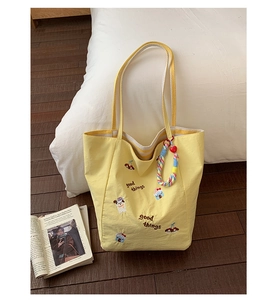 Détails de broderie de dessin animé et anses rayées sur sac cabas en toile jaune