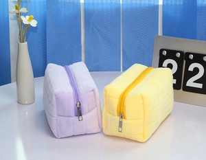 Close-up of quilted velvet pencil cases in lavender and lemon yellow with metal zippers