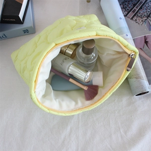 Detailed interior of bright yellow quilted makeup bag with skincare products inside