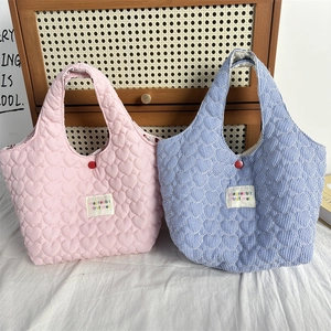 Detailed view of quilted tote bags featuring heart patterns and contrast snap closure