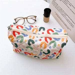 Macro shot of quilted floral makeup bag with colorful patterns and metal zipper detail