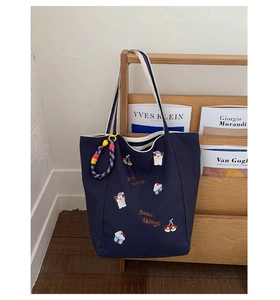 Détail du sac cabas en toile bleu marine avec broderie chien et pendentif tissé