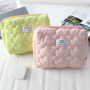 Detailed close-up of quilted cloud makeup bags in pastel yellow and soft pink colors