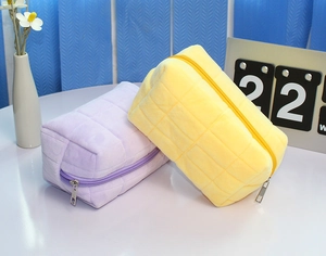 Close-up of purple and yellow plush quilted bags with soft flannel texture and zipper