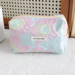 Detail of blue and pink floral embossed jacquard cosmetic bag with May Rabbit label