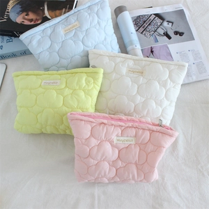 Flat lay of colorful quilted puffer makeup bags in pink, lime, cream and light blue