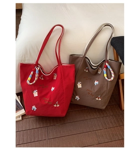 Détails de sacs cabas en toile rouge et marron avec broderie et anses tressées arc-en-ciel