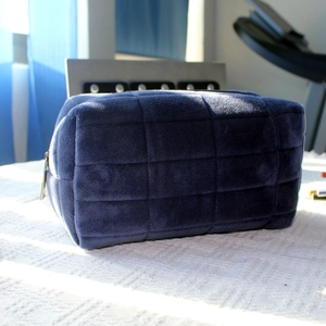 Macro detail of dark blue velvet quilted pencil case with silver zipper and soft texture