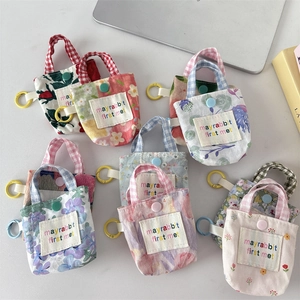 Détail de mini pochettes en tissu floral avec bouton-pression et crochets colorés