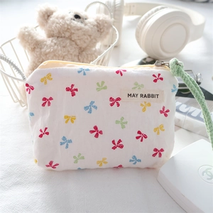 Detailed view of canvas mini pouch featuring colorful bow patterns and green hand strap