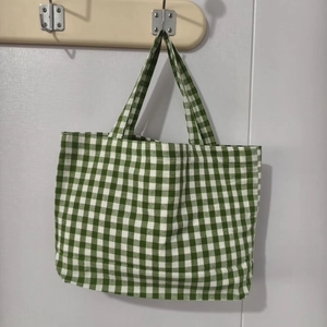 Close-up of green and white checkered canvas tote bag with reinforced handles