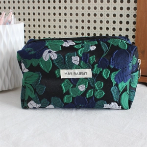 Detailed shot of black jacquard pencil case with blue floral patterns and fabric label