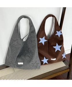 Detail of wool tote bags in grey and brown featuring star patterns and brand woven labels