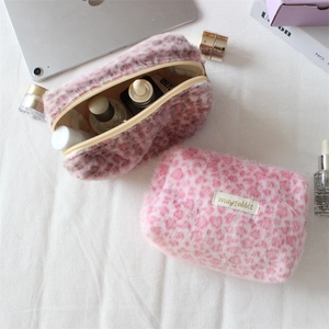 Dettaglio macro della borsa da trucco in peluche leopardato rosa con vari cosmetici
