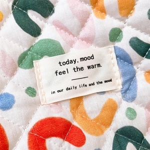 Macro shot of quilted cotton fabric with colorful geometric patterns and white woven label