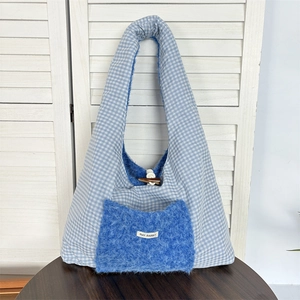 Close-up of blue and white plaid tote with plush pocket and wooden horn button detail