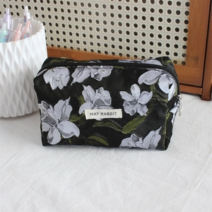 Macro view of floral jacquard fabric texture and brand label on the black pencil case