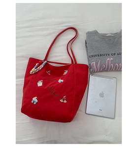 Détail du cabas en toile rouge avec broderie Good Things et écussons de dessins animés