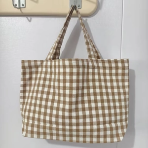 Close-up of brown and white gingham checkered canvas handbag with durable handles