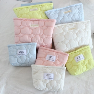 Detailed view of quilted cotton cosmetic bags in macaron colors with woven labels