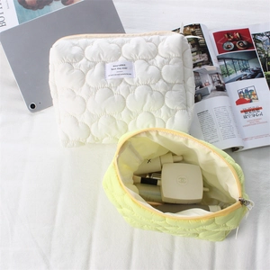 Detailed view of quilted makeup bags in cream and yellow with heart patterns