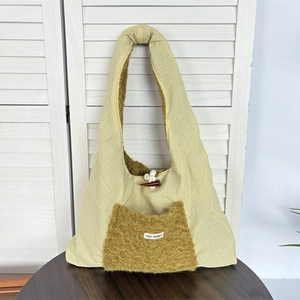 Detail of gingham shoulder bag featuring a plush faux fur pocket and horn button closure