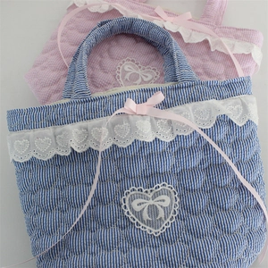 Close-up of quilted heart patterns and delicate lace edges on pink and blue bucket bags
