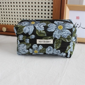 Detailed view of black floral jacquard pouch with blue flower patterns and zipper closure