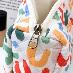 Macro shot of colorful floral quilted cotton bag with metal zipper and diamond stitching