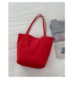 Détail d'un grand sac fourre-tout rouge en nylon avec de longues anses sur tissu