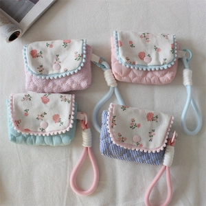 Close-up of floral quilted camera and earphone storage pouches with decorative pom-poms