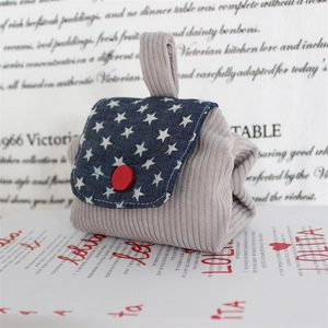 Detailed view of grey corduroy mini pouch with navy star denim flap and red button