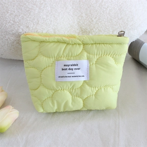 Detail of light green quilted cosmetic bag with cloud texture and metal zipper closure