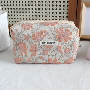 Close-up of floral jacquard fabric with pink embroidery and large ring zipper pull