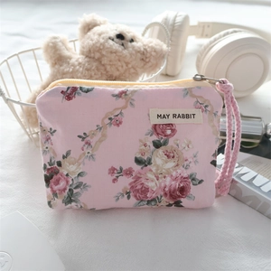 Detailed macro view of a pink floral mini pouch with ribbon bow and secure zipper closure