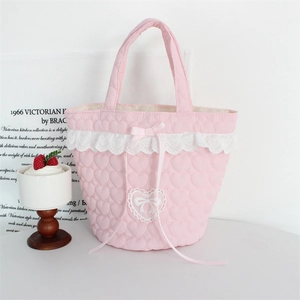 Detail of pink quilted bucket bag featuring heart patterns, lace trim and a sweet bow