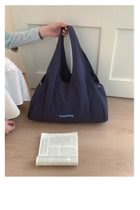 Detail of navy nylon tote bag showing wide shoulder strap and printed GoodThing lettering