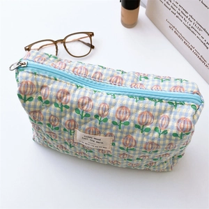 Quilted floral cosmetic bag with tulip pattern and blue zipper shown in lifestyle setup