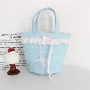 Detail of light blue quilted heart handbag with white lace trim and pink ribbon bow