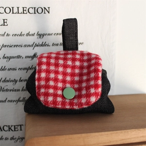Detail view of mini denim coin purse with red plaid flap on a wooden tabletop