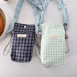 Detail of plaid crossbody bags with mint green and navy patterns and adjustable straps