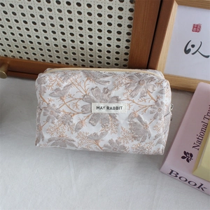 Close-up of vintage floral jacquard pouch with metal zipper and woven label detail