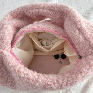 Internal view of a pink plush handbag showing a small inner pocket and daily essentials