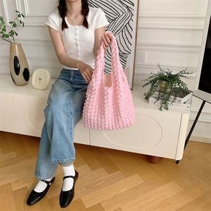 Close-up of pink bubble texture tote bag with popcorn pleated design held by a model