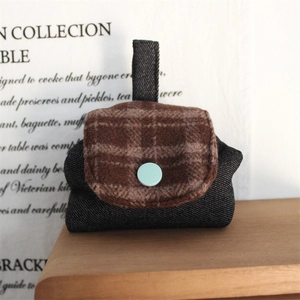 Detail of a mini retro fabric pouch with plaid flap and blue button for accessories