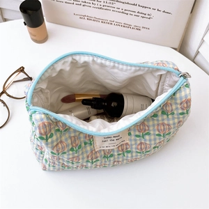 Detailed view of quilted cotton cosmetic bag with tulip print and blue zipper closure