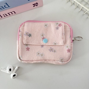 Detail of pink floral corduroy pouch with blue button pocket and gold zipper ring